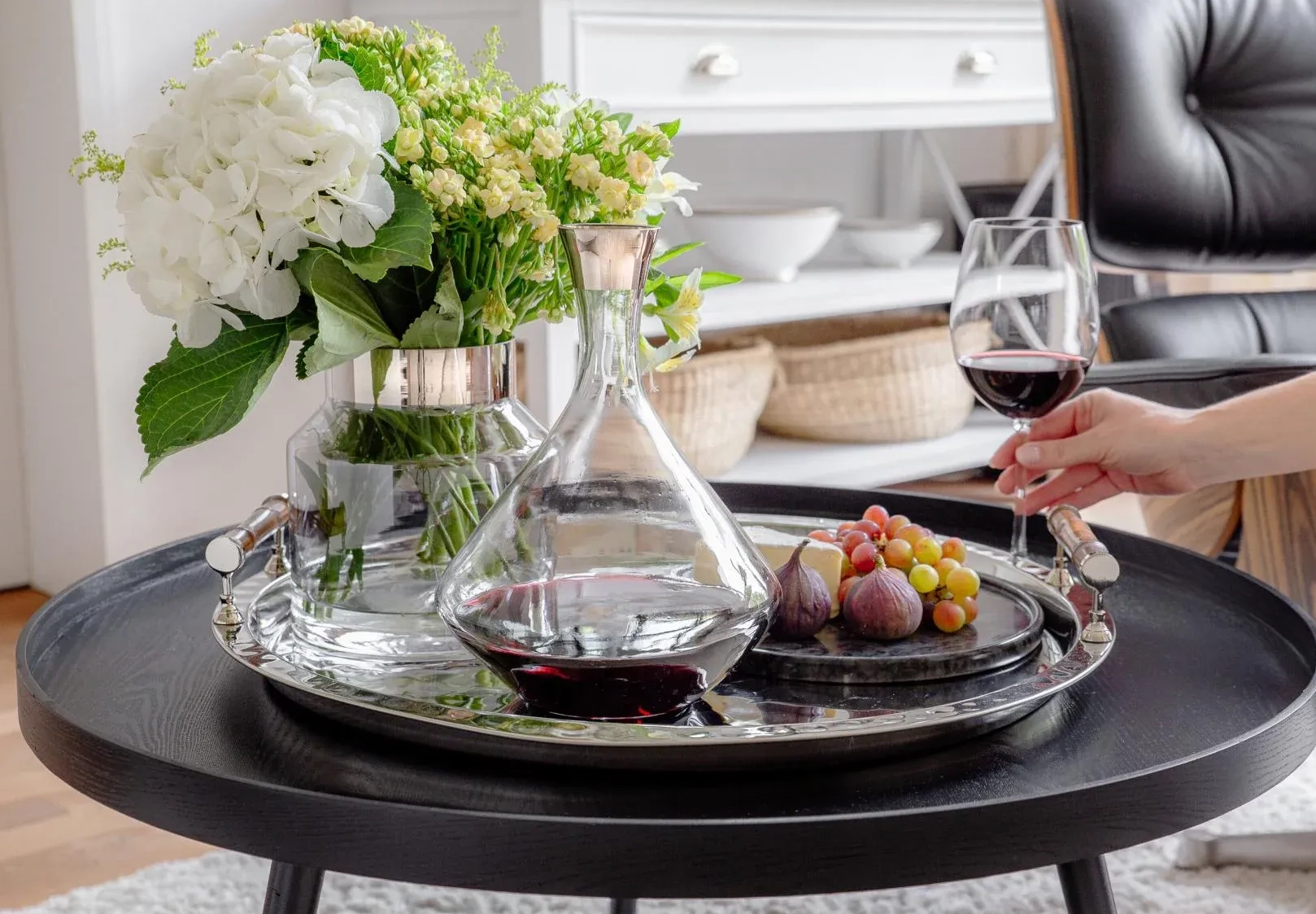 Weindekanter aus Glas mit Rotwein auf Serviertablett im Wohnbereich